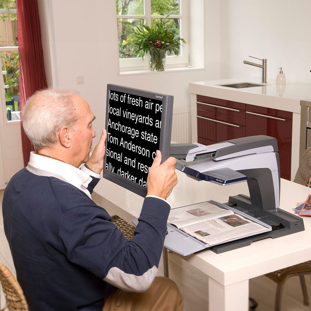 Older man using the ultra flexible arm on ClearView+ for a better reading position