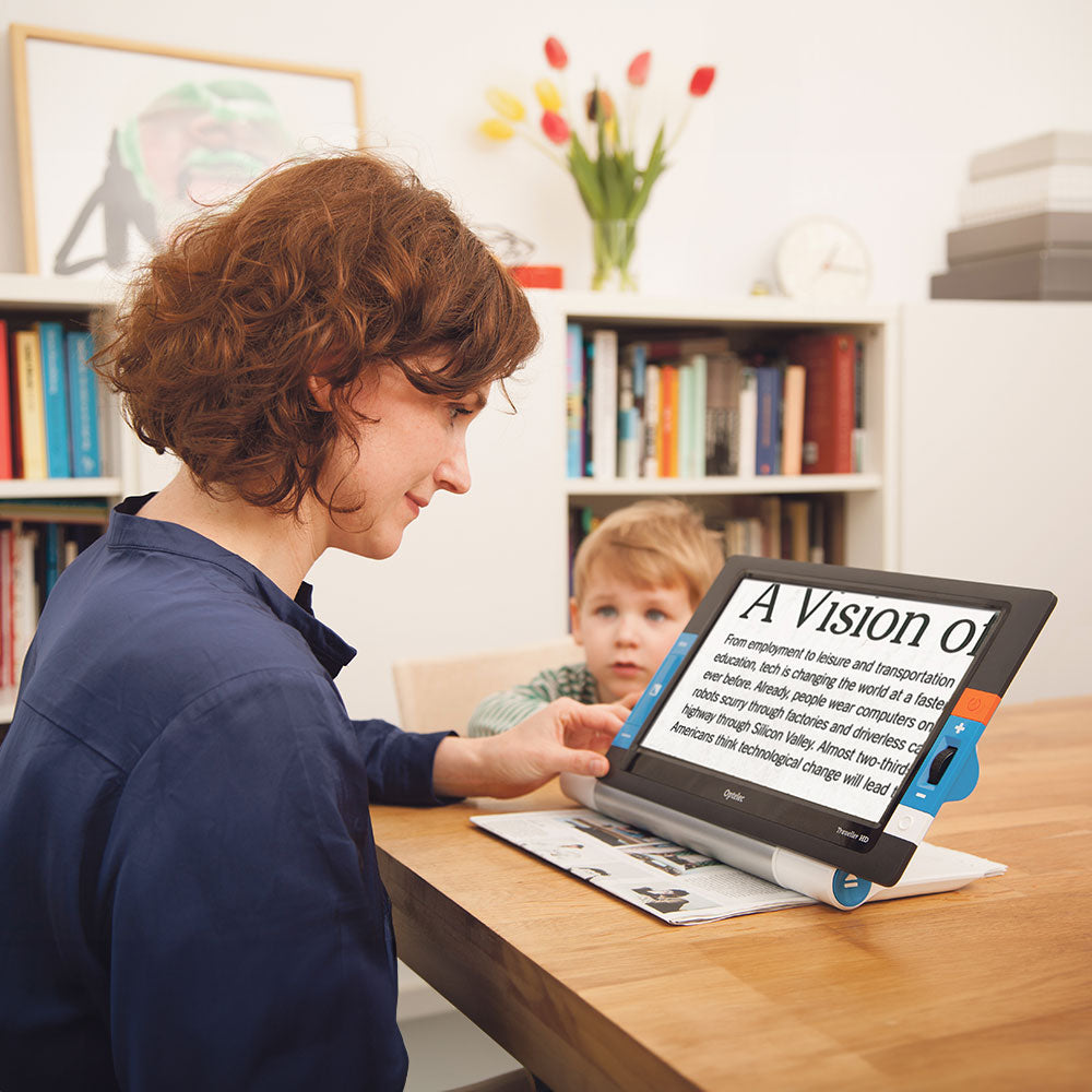 Woman magnifying a newspaper with Traveller HD as child watches her